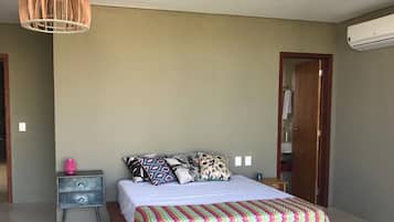 A bedroom with a bed, bedside tables, a hanging light fixture, and an air conditioning unit.