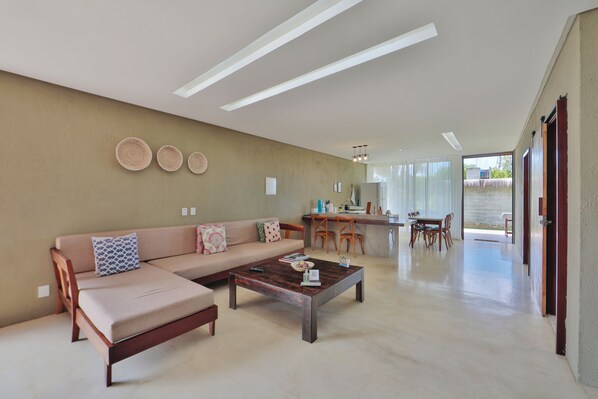 A modern living room with a sofa, coffee table, and dining area. - Bahay Tatu Home Concept (Porto de Pedras)