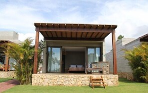 A modern outdoor lounge area with a stone base, wooden furniture, and a pergola. - Bahay Tatu Home Concept (Porto de Pedras)
