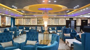 A hotel lobby with blue upholstered seating, a chandelier, and a patterned wall. - The Castle hotel (Amman)