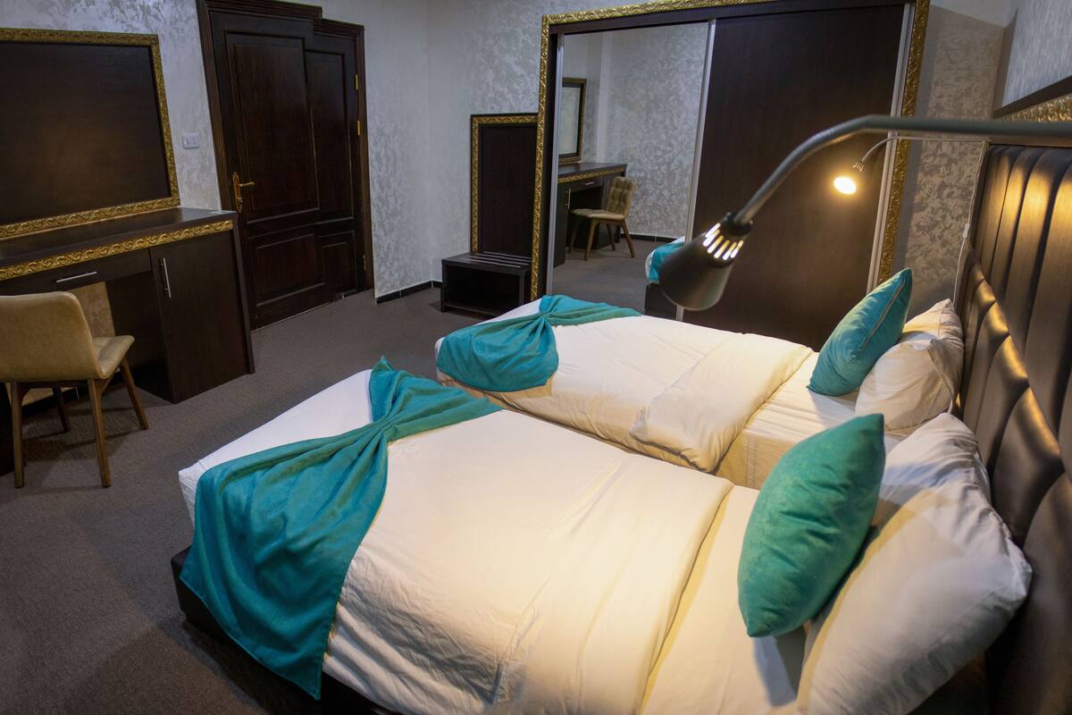 A hotel room with two beds, a desk, and a chair.