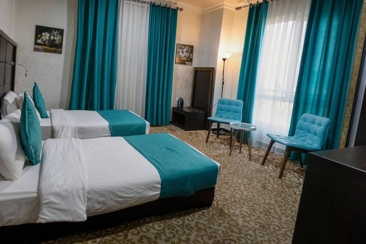 A hotel room with two beds, a desk, and a chair.