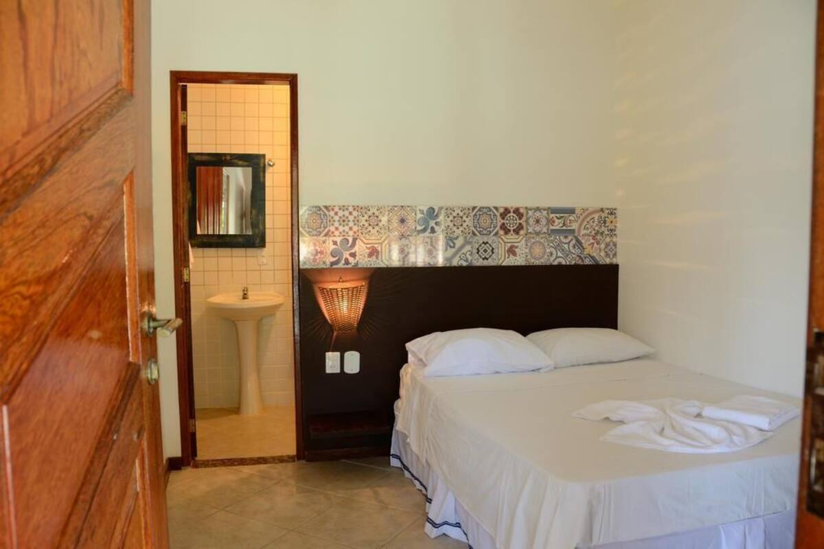 Una habitación de hotel con una cama, un lavamanos y un espejo.