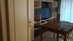 A room with a wooden table, a white door, and a built-in shelving unit with various items. - Renovated apartment 3 floor with elevator in Prati (Roma)