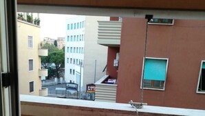 A balcony with a pink table and colorful chairs, overlooking a cityscape with buildings and a signboard. - Renovated apartment 3 floor with elevator in Prati (Roma)