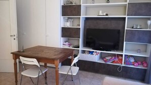 A room with a wooden table and two chairs, a television on a shelf, and various items on the shelves. - Renovated apartment 3 floor with elevator in Prati (Roma)
