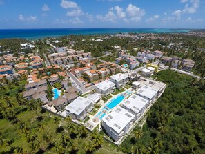 An aerial view of a resort with multiple buildings, a swimming pool, and a view of the ocean. - Costa Hermosa C302LO_200Mpbs_Pool_BBQ_Walk to the Beach (Bavaro-Punta Cana)