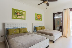 A hotel room with two beds, a ceiling fan, and artwork on the walls. - Costa Hermosa C302LO_200Mpbs_Pool_BBQ_Walk to the Beach (Bavaro-Punta Cana)