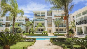 Un hotel moderno con varios pisos, piscina y jardines bien cuidados.