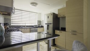 A modern kitchen with a central island, stainless steel appliances, and light wood cabinetry. - Playa Turquesa I201 LO_200 Mbps_Private Beach Access_BBQ (Bavaro-Punta Cana)