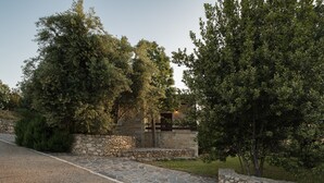 A stone pathway leading to a stone building with a modern design, surrounded by lush greenery. - Koules Estate-Anemone, with Pool & BBQ, an Agricultural barn for Nature lovers (Rethymno)