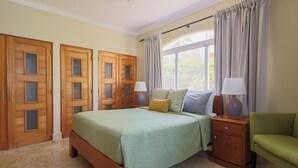 Une chambre à coucher avec un lit, des tables de chevet, une chaise et des portes en bois.