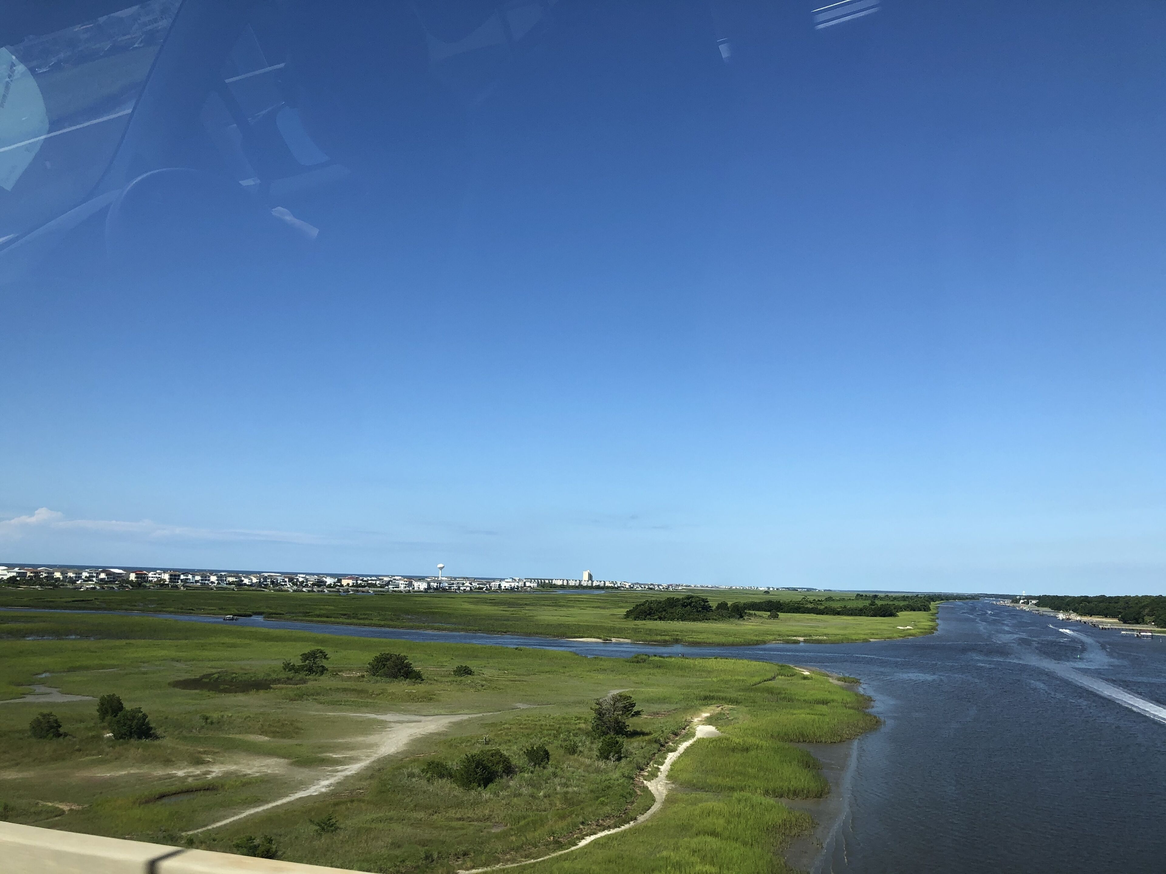 A river with a path alongside it, a bridge, and a distant town.