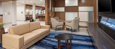 A modern lobby with a sofa, chairs, a small table, and a fish tank.