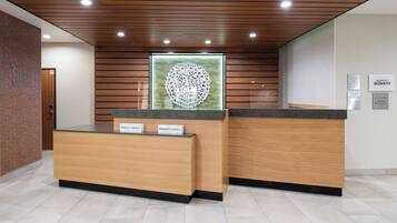 A hotel reception desk with two counters, a wooden ceiling, and a wall-mounted decorative piece.