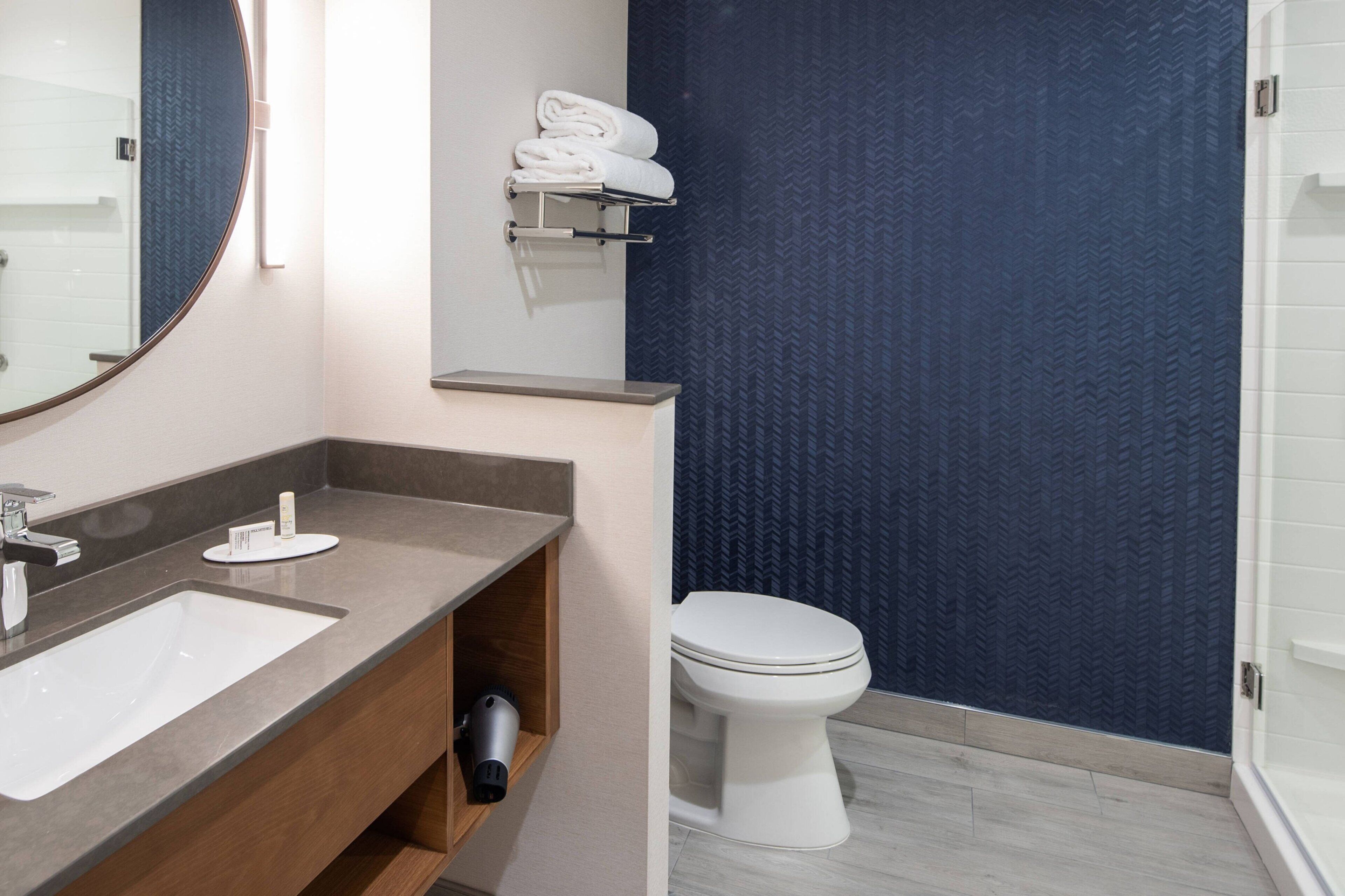 A modern bathroom with a large sink, a mirror, a towel rack, and a toilet.