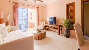A living room with a sofa, a coffee table with decorative items, a television, a wooden cabinet, and a potted plant. - Estrella del Mar G5LO_200Mbps_BBQ_Walk to Beach! (Bavaro-Punta Cana)