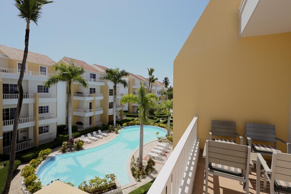 Un patio de hotel con piscina, palmeras y sillas de descanso.