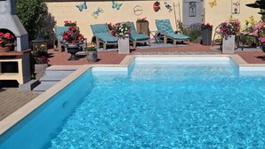 Una piscina con sillas de descanso y plantas en macetas.