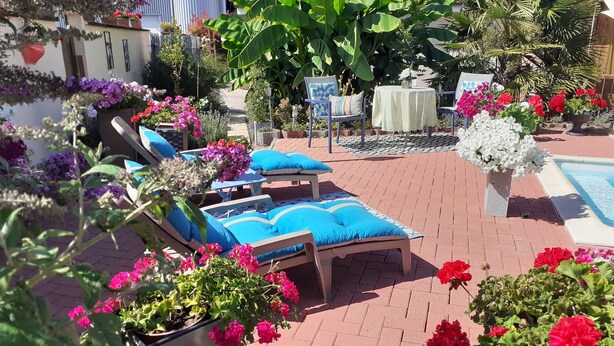 Un patio con sillones de descanso, una pequeña mesa y una piscina.