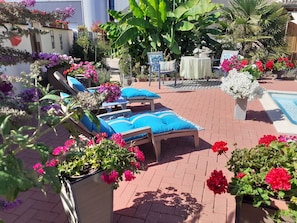 Un espace patio aménagé avec des chaises longues, une petite table et une piscine.