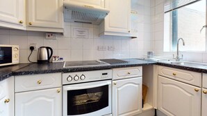Een keuken met witte kastjes, een fornuis, oven en een magnetron.