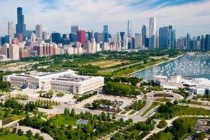 Vista aérea de un paisaje urbano con un complejo arquitectónico destacado, un río y zonas verdes circundantes.