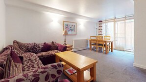 Ein Wohnzimmer mit einer Couch, einem Holztisch und einem Essbereich mit Stühlen.