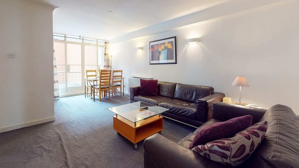 A modern living room with a glass coffee table, a leather sofa, and a dining area with chairs and a table. - Luxury Serviced Apartment, Staffed Reception, Two Bathrooms, Large Living Room a (London)