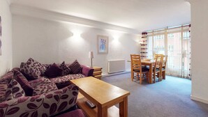 A living room with a sofa, a wooden table, and a dining area with chairs. - Luxury Serviced Apartment, Staffed Reception, Two Bathrooms, Large Living Room a (London)