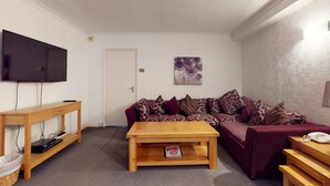 A living room with a sofa, a coffee table, a TV on a stand, and a door. - Luxury Serviced Apartment, Staffed Reception, Two Bathrooms, Large Living Room a (London)