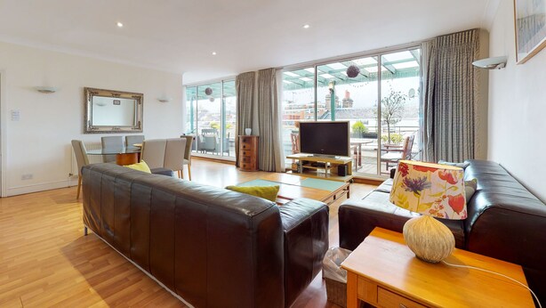 Ein geräumiges Wohnzimmer mit einer Ledersofa, einem Holztisch und einem Fernseher.