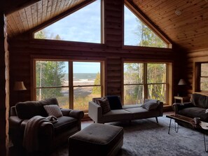 Eine Holzhütte mit großen Fenstern und einer gemütlichen Sitzecke mit Sofa und Sesseln.