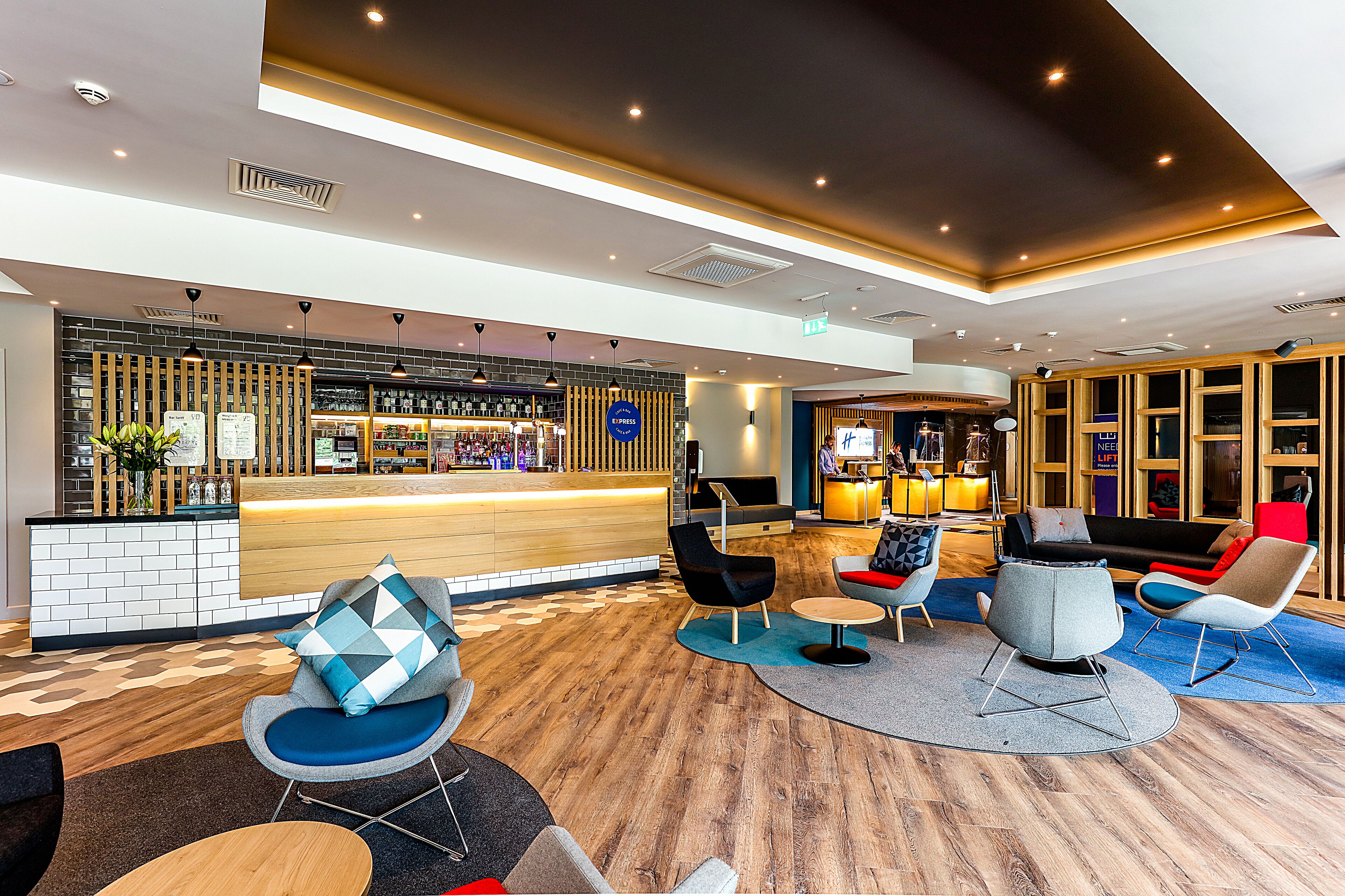 A modern lobby with a reception desk, seating area, and a bar.