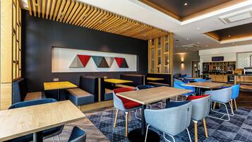 A modern restaurant interior with booths, tables, and a bar area.