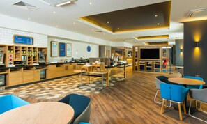 A modern cafe with a breakfast bar, seating area, and a TV screen. - Holiday Inn Express Bicester by IHG (Bicester)