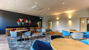 A modern interior with round tables and chairs, a geometric wall art piece, and a patterned carpet.