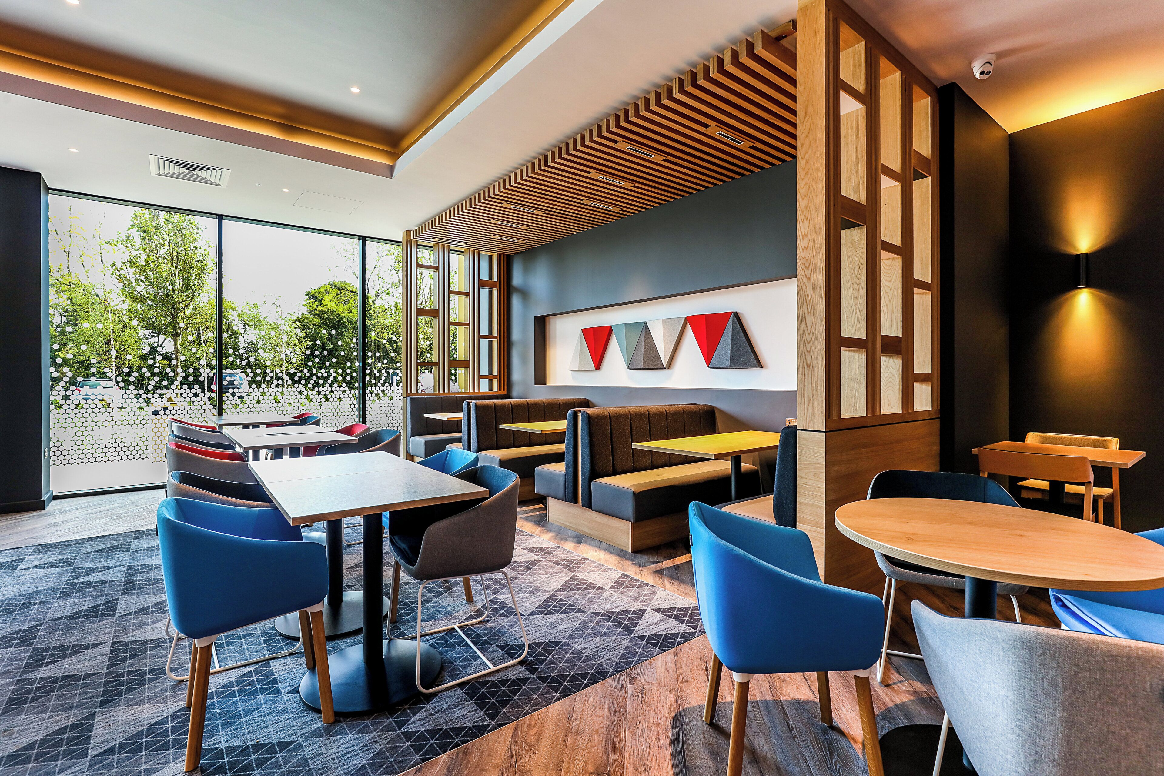 A modern interior with seating arrangements, a patterned ceiling, and a view through a glass door.
