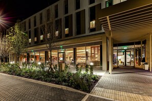 A modern hotel with a glass facade, outdoor seating area, and a landscaped garden. - Holiday Inn Express Bicester by IHG (Bicester)