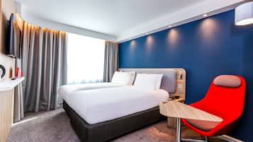 A hotel room with a large bed, a desk, a chair, and a TV.