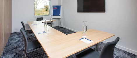 A conference room with a long table, chairs, a projector screen, and a whiteboard.