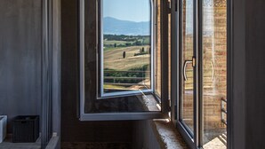 Una stanza con un'ampia finestra ad arco che si affaccia su un paesaggio rurale.