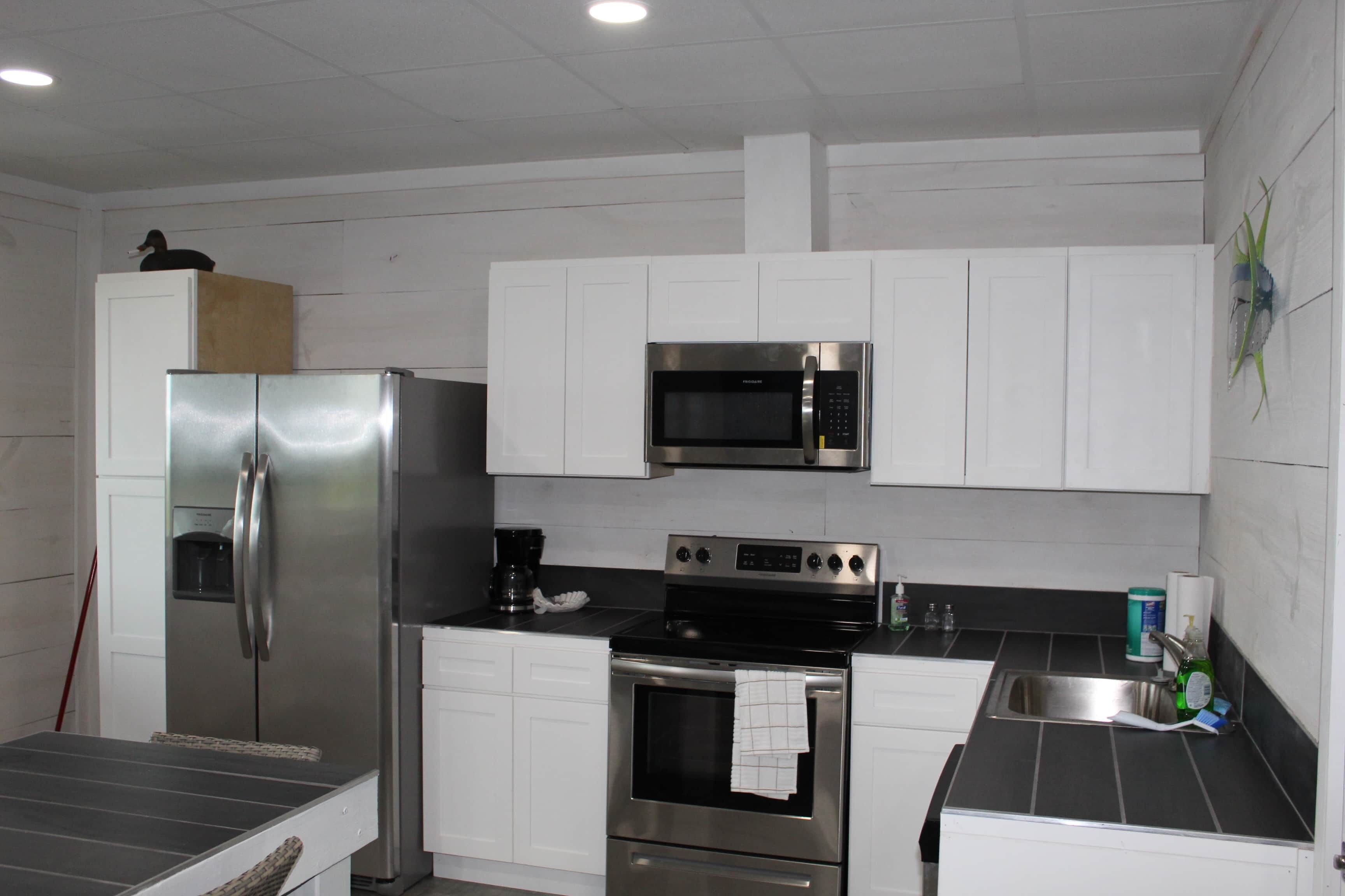 Una cocina con gabinetes blancos, electrodomésticos de acero inoxidable, un microondas y un fregadero.