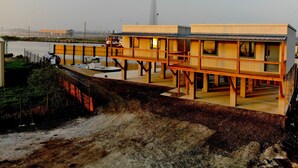 A waterfront hotel with a deck, a water body in the background, and a tall communication tower. - Venice Blue Crab Lodge B (Waterfront) (Venice)