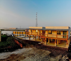 A two-story building with a flat roof, a dock extending into a body of water, and a tall communication tower in the background.