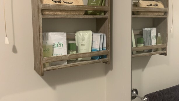 A bathroom with a wooden shelf holding toiletries and a mirror above it. - High Greenside Farmhouse B&B (Kirkby Stephen)