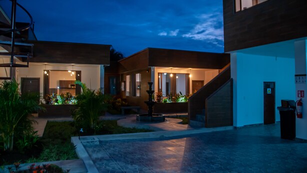 A modern building with a courtyard, a fountain, and a staircase leading to the entrance. - Toucan Platinum Suites Aparthotel (Mindo)