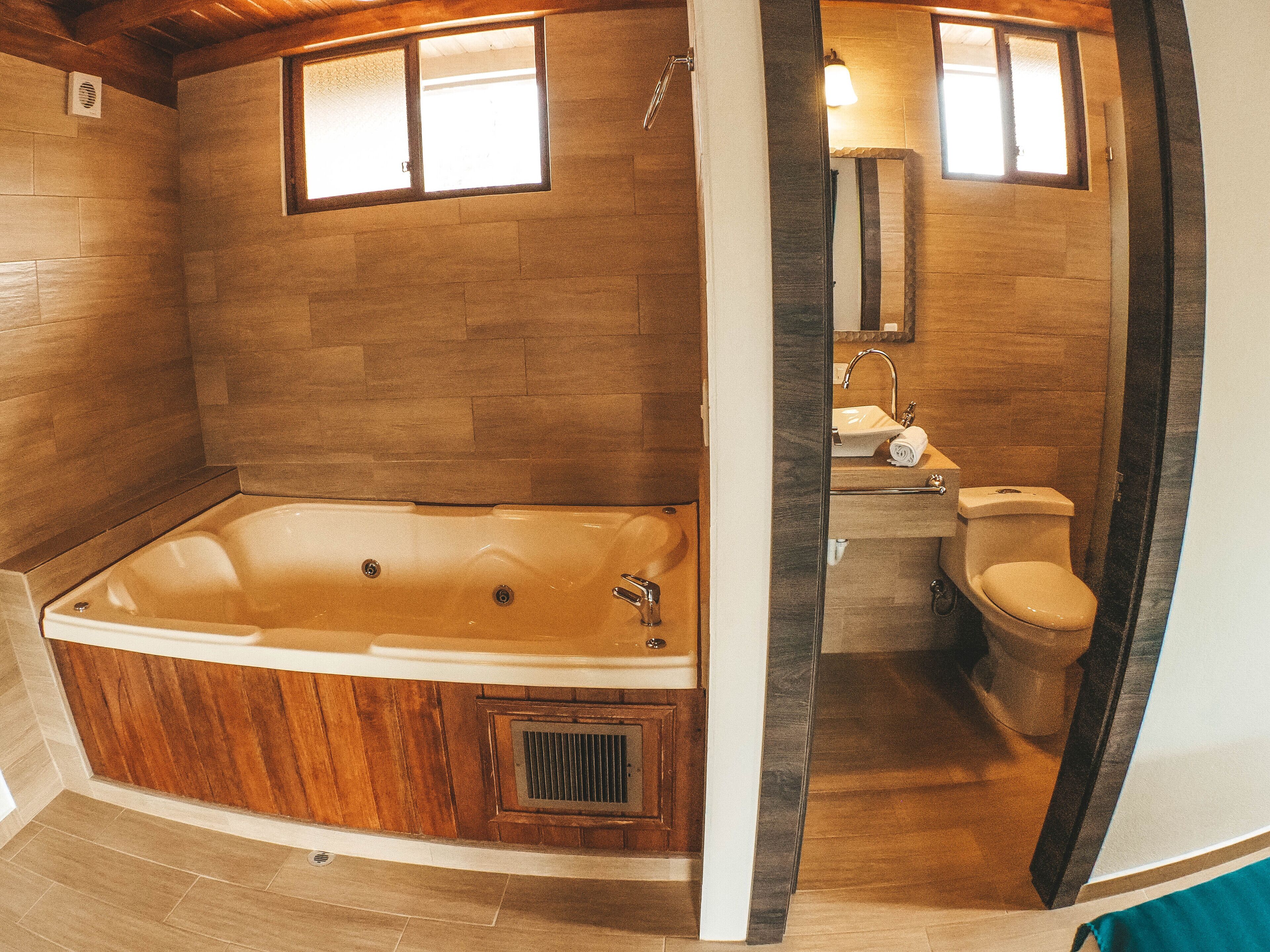 A bathroom with a wooden bathtub, a sink, and a toilet.