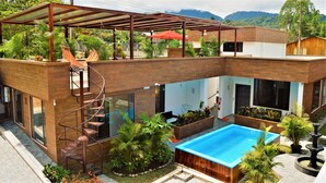 A modern two-story house with a rooftop garden, a spiral staircase, a swimming pool, and a covered patio area. - Toucan Platinum Suites Aparthotel (Mindo)