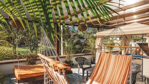 A hammock lounge area with a view of the garden and a wooden deck. - Toucan Platinum Suites Aparthotel (Mindo)
